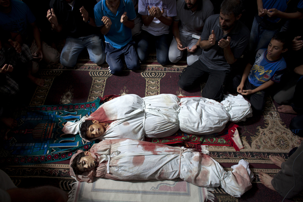 Miembros de una familia rezan en la Mezquita de Sajeria junto a los cuerpos de Amir (15), Mustafa Arief y Mohammed durante su funeral en Sajeria, Gaza, en julio del 2014. 