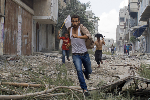 Hombres palestinos corren con una bandera blanca en el bombardeado barrio de Shejaiya, Gaza (2014)