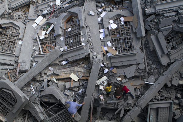 Los palestinos recogen libros religiosos musulmanes entre los escombros de la mezquita Al-Qassam, en la Franja de Gaza (2014)